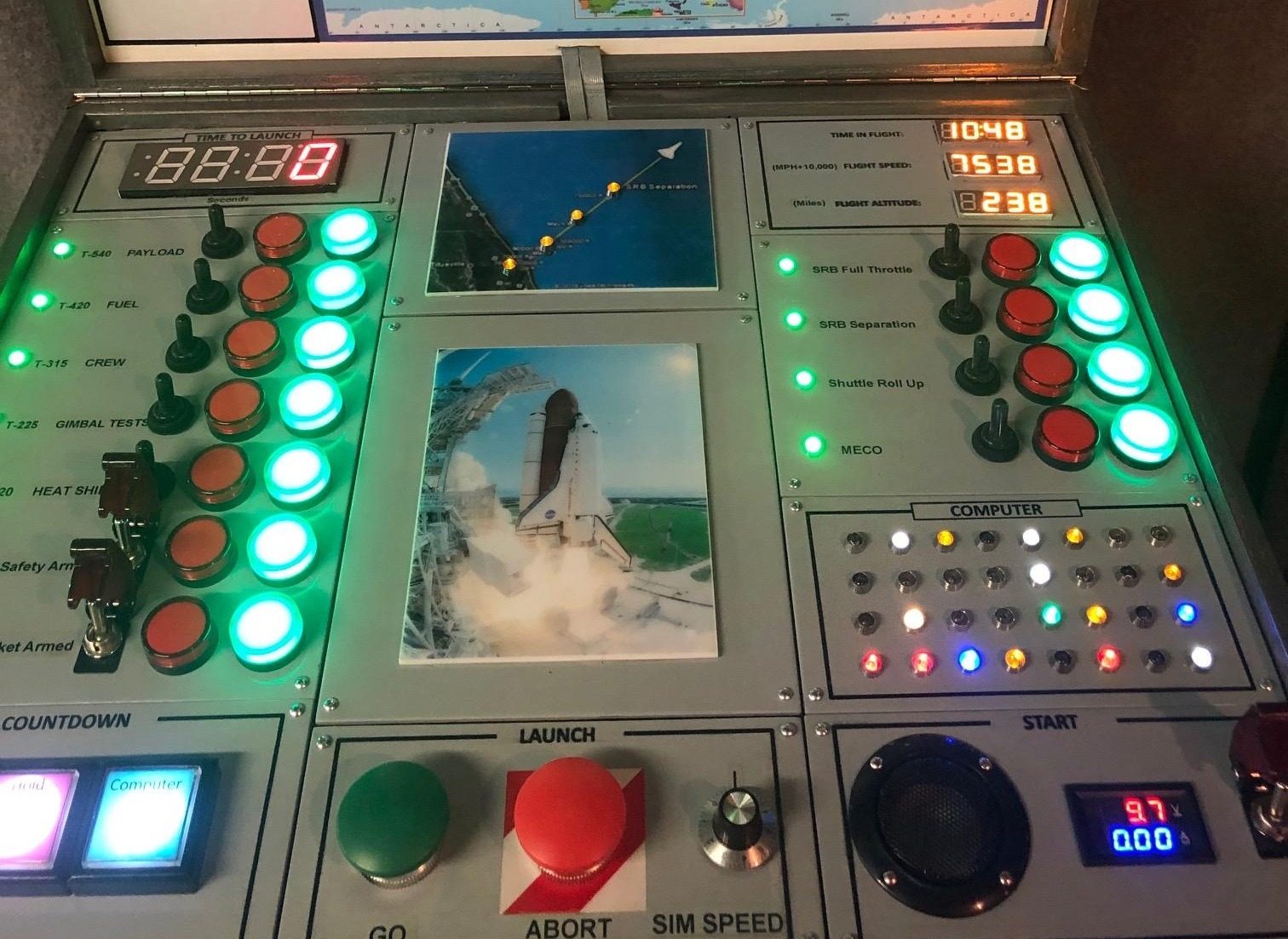An elaborate hand-built mission control panel with rows of glowing switches, buttons and displays.