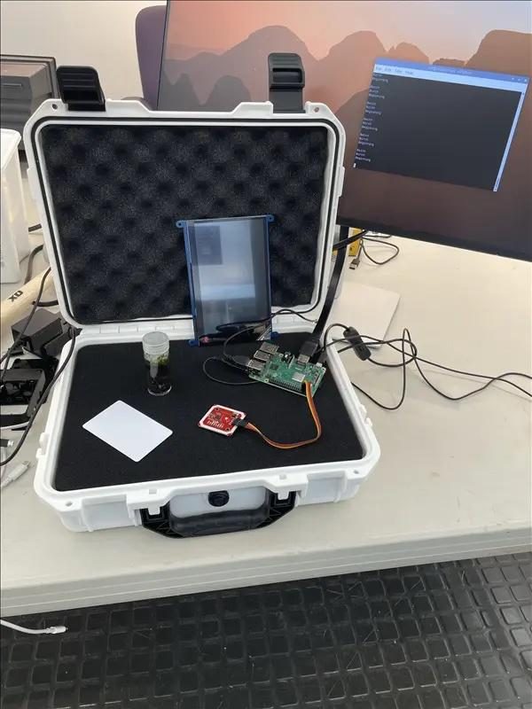 A rugged Pelican case opened on a desk, holding a small screen, a Raspberry Pi and an NFC reader.
