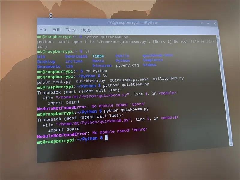 A photograph of a small screen showing a terminal window with Python errors and command output.