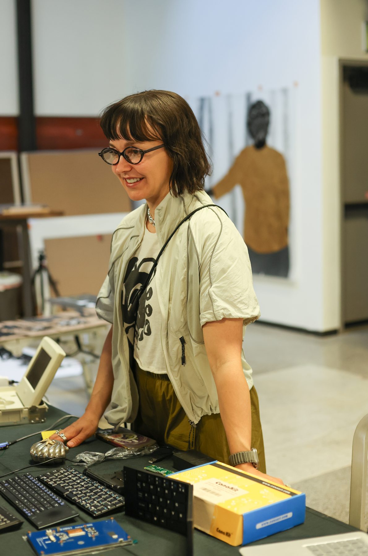 Meghan Thréinfhir at her table with keyboards and a wire-shaped ornament, laughing.