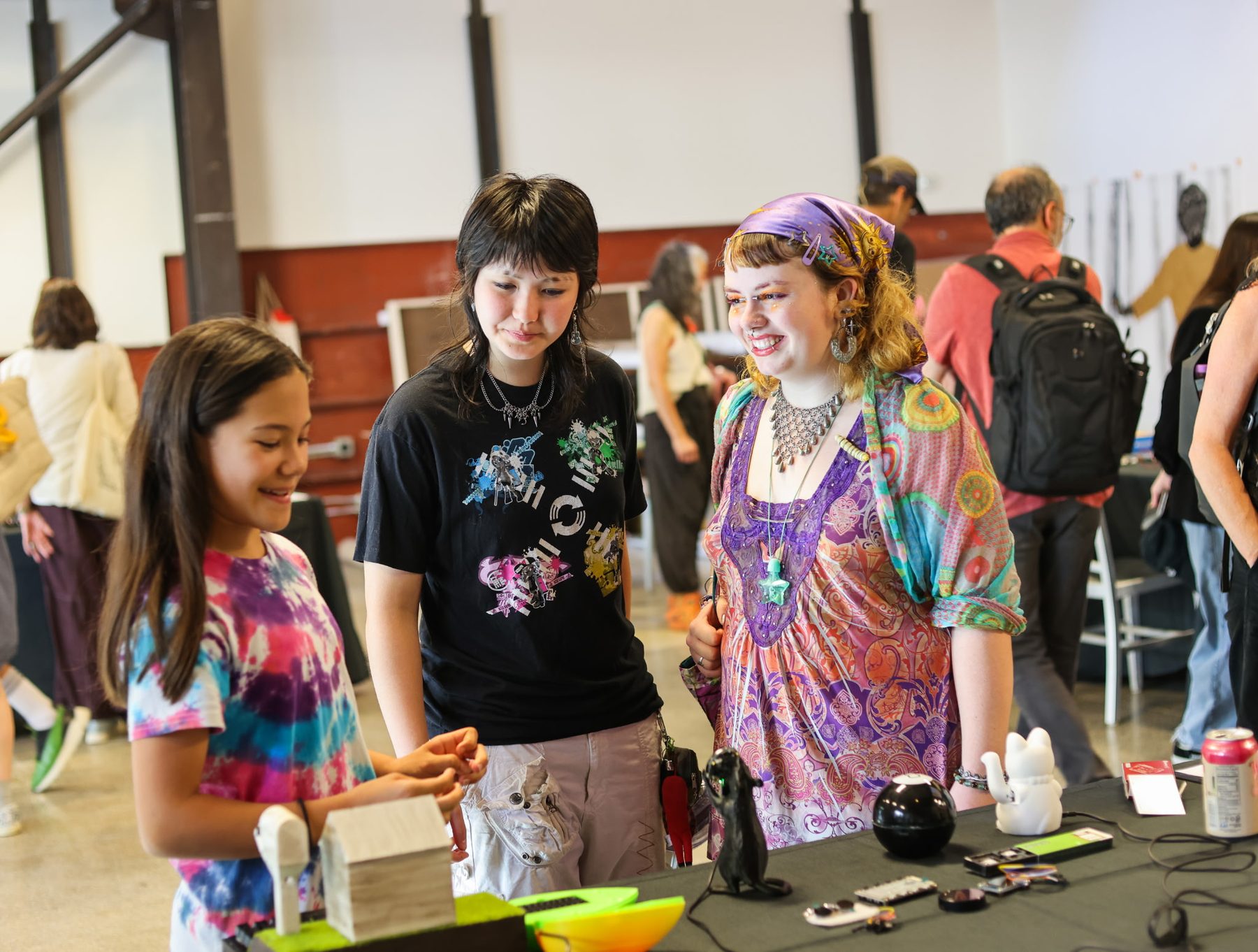 Three visitors leaning over a table of cyberdecks together.